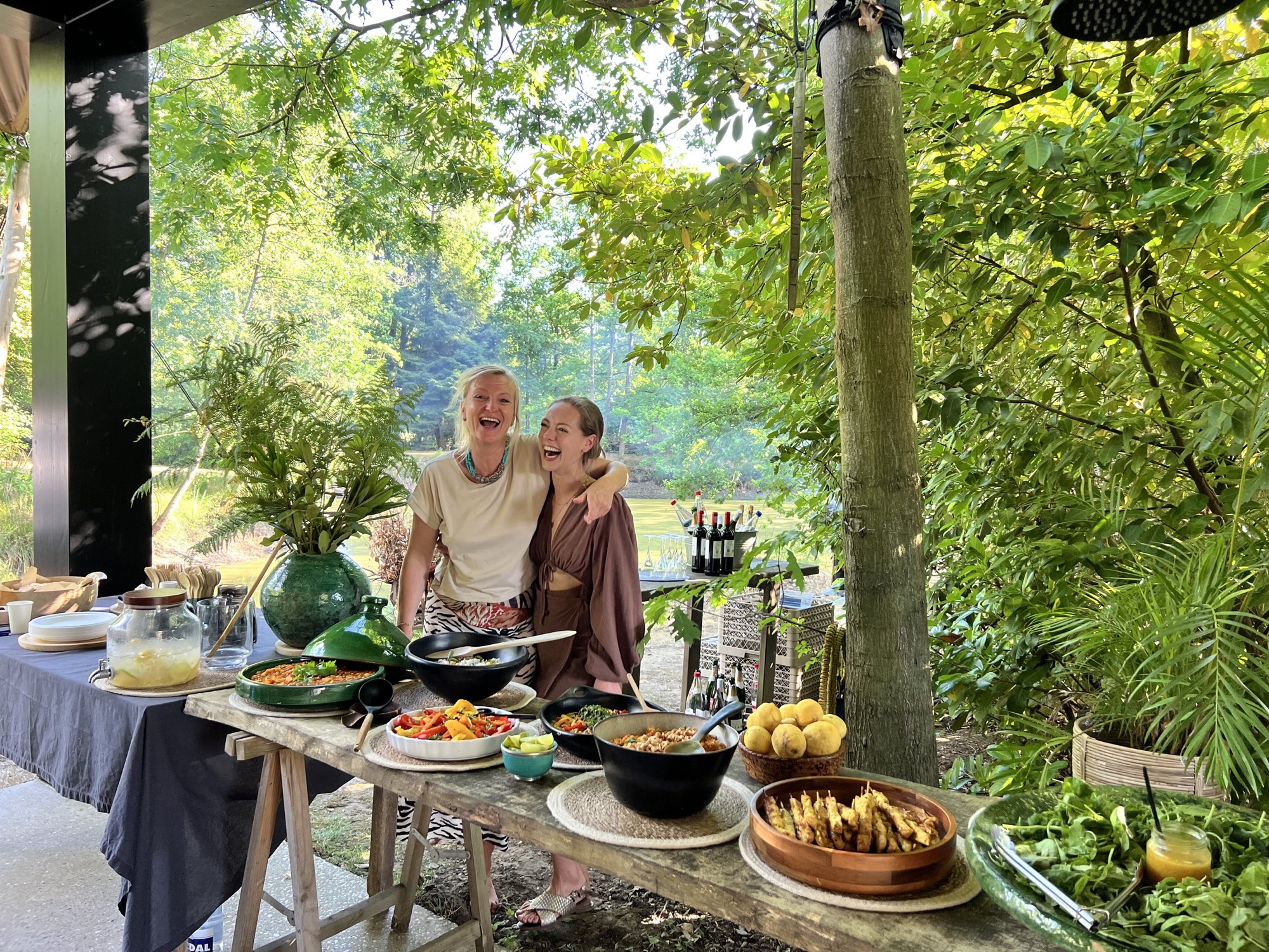 Gedekte tafel vol gerechten en gelach tijdens een gedeelde maaltijd in de natuur